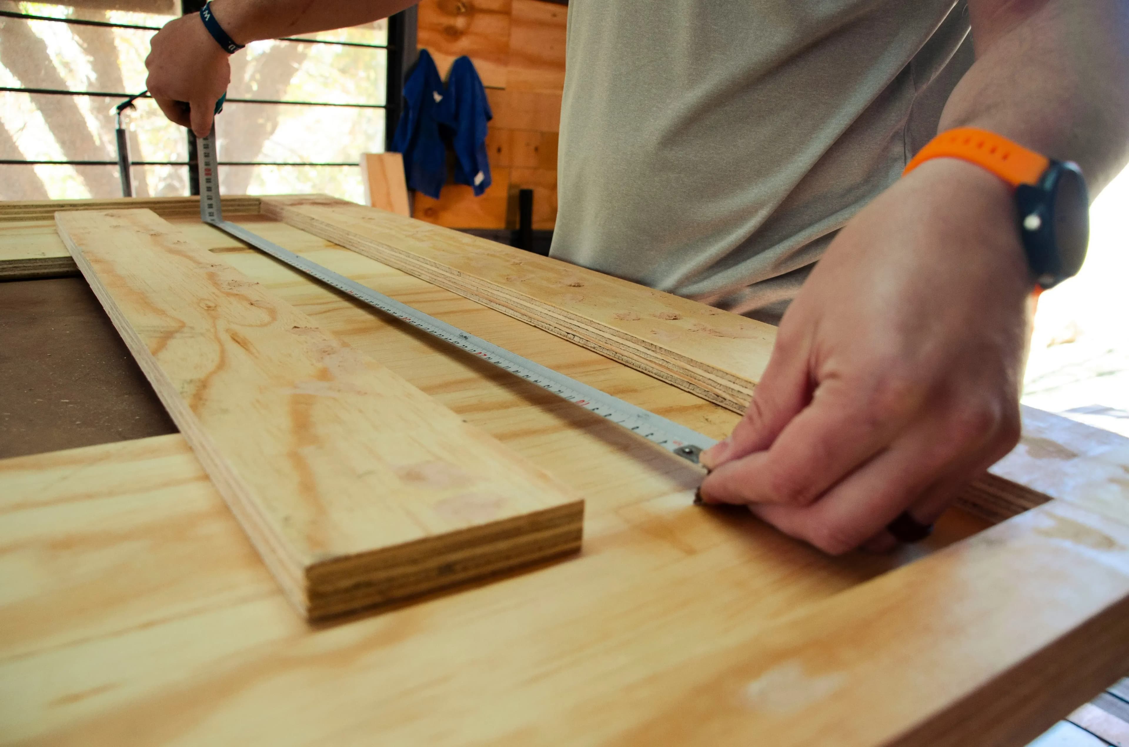 Un menuisier prend les mesures d'une planche de bois.