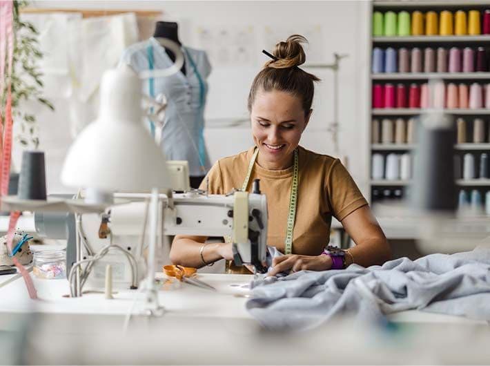 Couturiére experte de la mode sur vêtement flou entrain de coudre une tenue