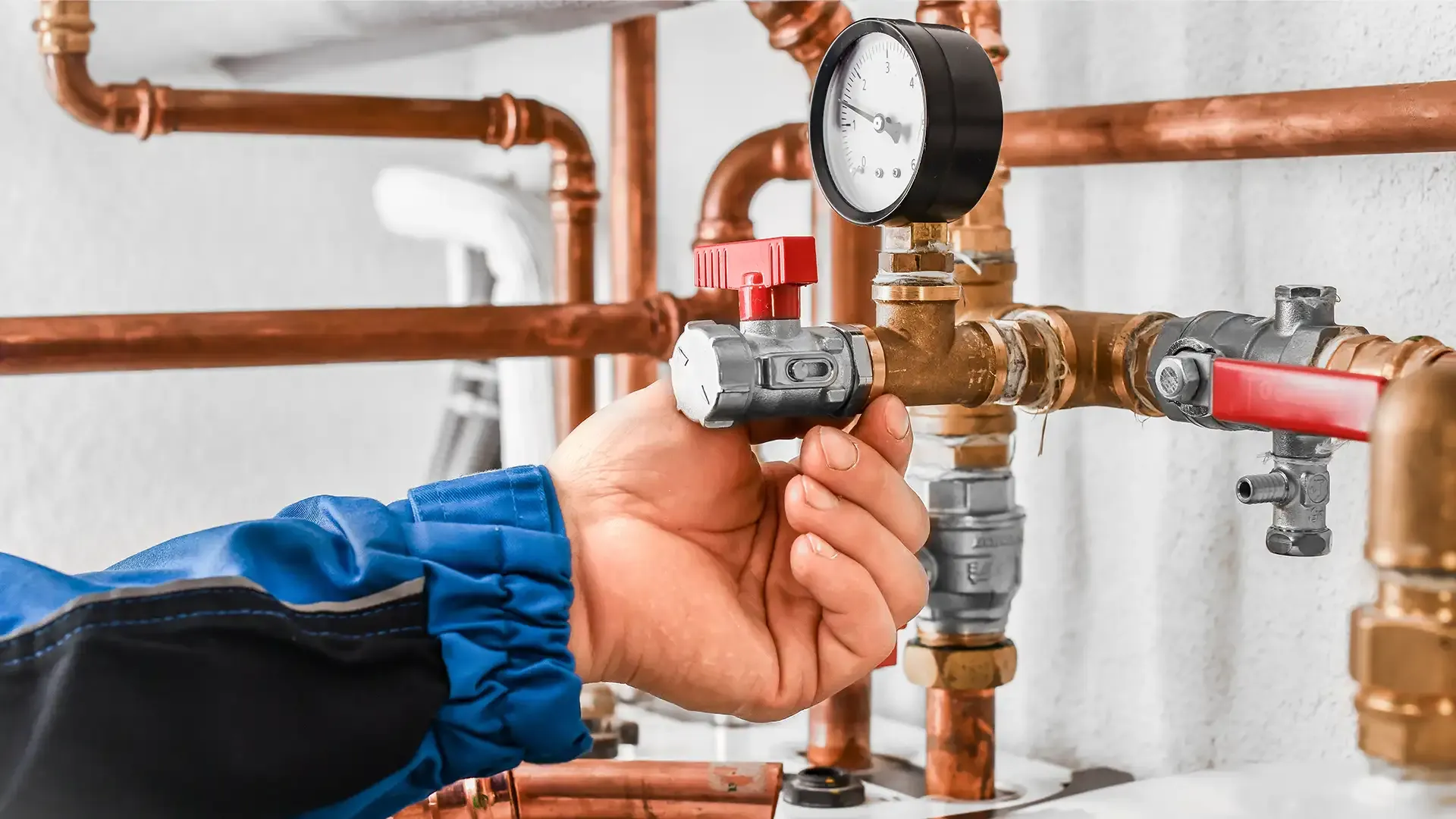 Un plombier-chauffagiste diplômé d'un CAP MIT avec Skill & You, réalise une opération de contrôle sur de la tuyauterie de chauffage.