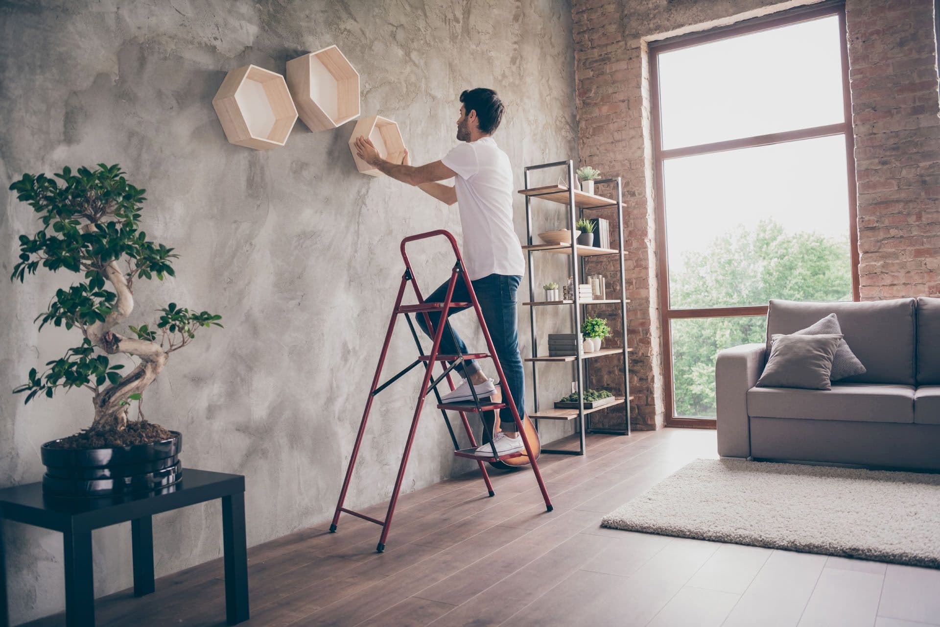 Un décorateur d’intérieur entrain d'installer une décoration au mur